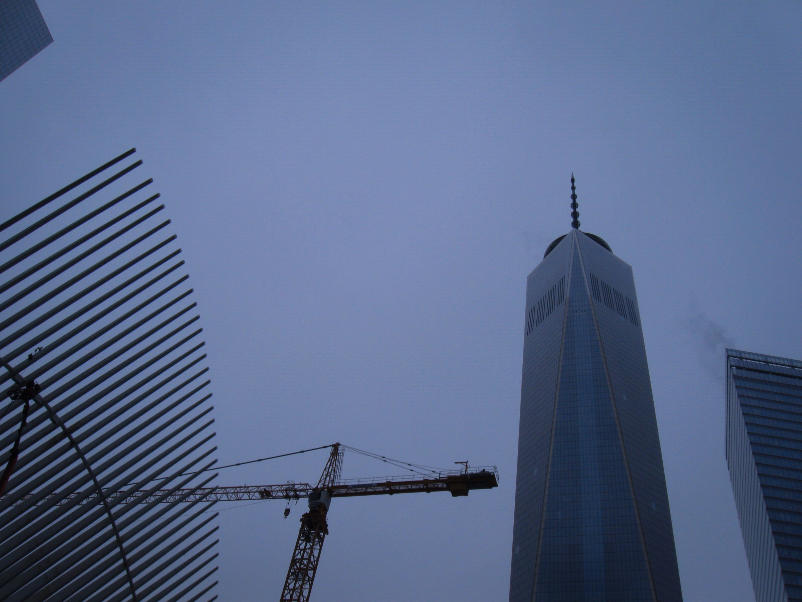 looking up at the top of one world trade center, with a construction crane to the left